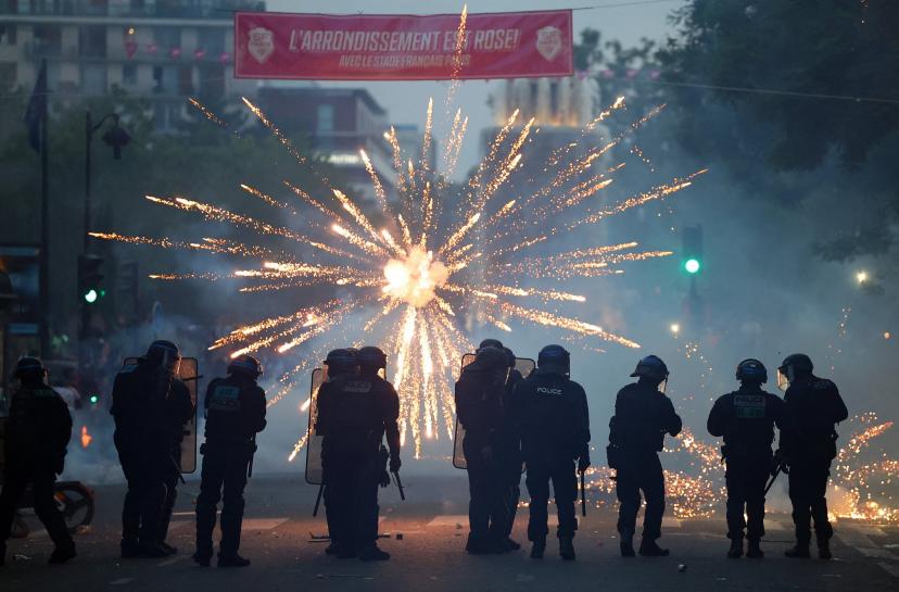 Fireworks explode in front of riot police in Paris after PSG's Champions League victory