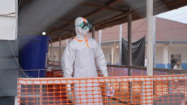 Health workers in protective gear attending to patients in a medical facility during the Ebola outbreak